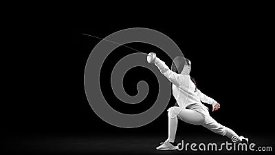 Energetic female fencer in white fencing costume and mask in action, motion isolated on dark background. Sport, youth Stock Photo