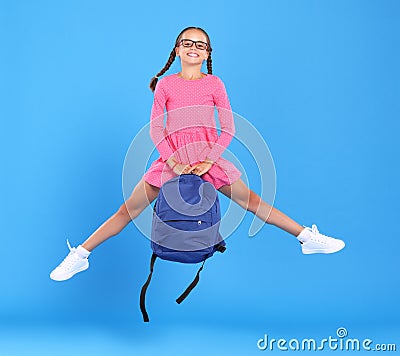 Energetic happy schoolgirl in eyewear with funny surprised facial expression jumping up in air Stock Photo