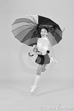 Energetic look. Adorable girl jumping with autumn look on yellow background. Cute little schoolchild having glamour look Stock Photo