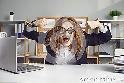 Funny office worker sitting at desk and flexing muscles happy to start working day Stock Photo