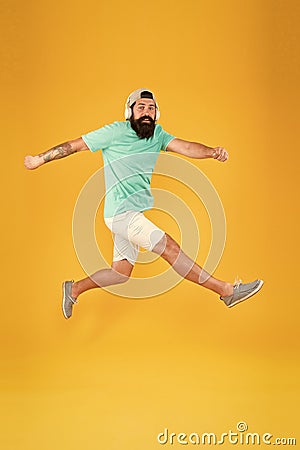 Energetic and upbeat music for leisure. Energetic hipster jumping high on yellow background. Bearded man in mid air Stock Photo