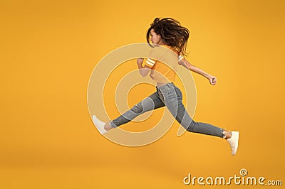 Energetic woman running or jumping. Skinny jeans suits her. Sexy girl yellow background. Sensual girl in casual style Stock Photo