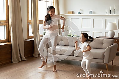 Energetic young vietnamese ethnic mother dancing with kid daughter. Stock Photo