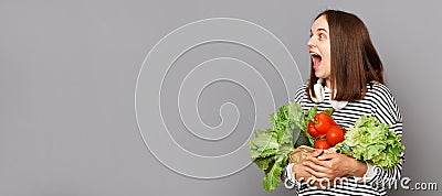 Energize with vitamin-rich vegetable. Surprised woman holding vegetables isolated over gray background, advertisement area, copy Stock Photo