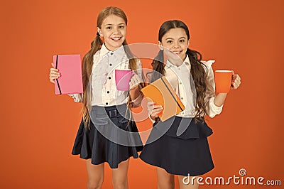 Energize your day. Cute schoolgirls holding cups and books. Little children drinking morning tea or milk. School Stock Photo