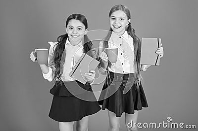 Energize your day. Cute schoolgirls holding cups and books. Little children drinking morning tea or milk. School Stock Photo