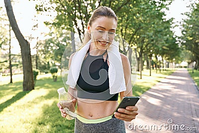 Energize your morning. Cheerful fit woman in sportswear refreshing, drinking water and using her smartphone after Stock Photo