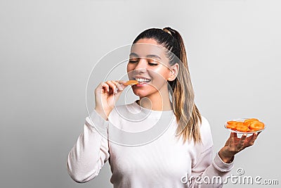 Energize yourself in the morning. beautiful and happy woman eating carrot on grey background Stock Photo