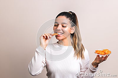 Energize yourself in the morning. beautiful and happy woman eating carrot on light background Stock Photo