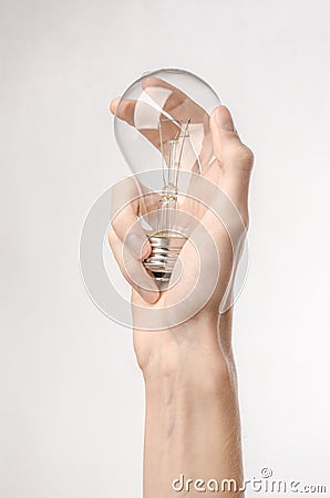 Energy consumption and energy saving topic: human hand holding a light bulb on a white background in studio Stock Photo