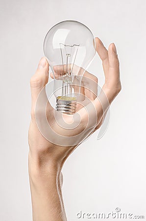 Energy consumption and energy saving topic: human hand holding a light bulb on a white background in studio Stock Photo