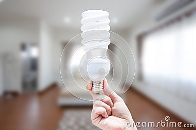 Energy saving concept, Woman hand holding light bulb on room house background Stock Photo