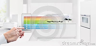 energy saving and smart home automation control concept hand touch screen of cell phone with efficiency class symbol on blurred k Stock Photo
