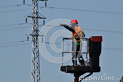 Equipped electrician near the electricity transmission line Editorial Stock Photo