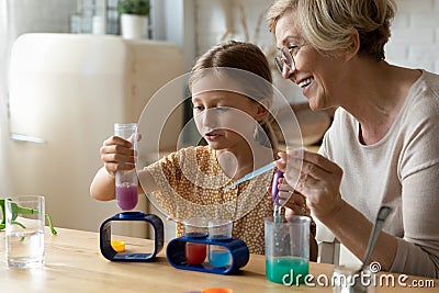 Mature woman tutor teach small girl chemistry in education game Stock Photo