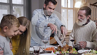 Enge, angenehme fröhliche Verwandte verschiedener Generationen, die darauf achten, Brattruthühner während der Familie zu schneide Enge, angenehme fröhliche Verwandte verschiedener Generationen, die darauf achten, Brattruthühner während der Familie zu schneide