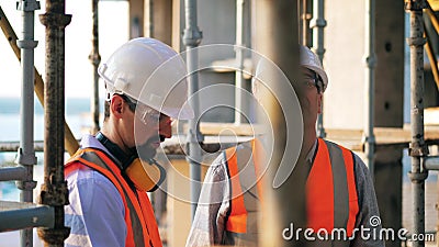 Engenheiros masculinos falando em um canteiro de obras Engenheiros masculinos falando em um canteiro de obras
