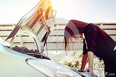 The woman looked at the engine broken while traveling. She looked in frustration. Stock Photo