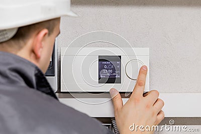 Engineer adjusting thermostat for efficient automated heating system Stock Photo