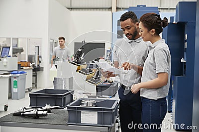 Engineer And Apprentice Meet On Floor Of Engineering Workshop Stock Photo