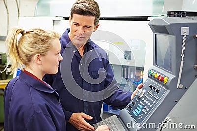 Engineer And Apprentice Using Automated Milling Machine Stock Photo