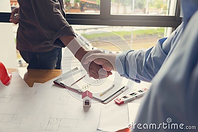 Engineer and Architect concept, Engineer Architects office team working shaking hand with blueprints and house model on office des Stock Photo