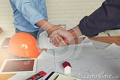 Engineer and Architect concept, Engineer Architects office team working shaking hand with blueprints and house model on office des Stock Photo