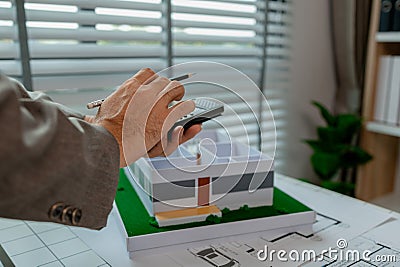 An engineer is calculating whether the structural proportions of a house model are correct with a calculator, an architect is Stock Photo
