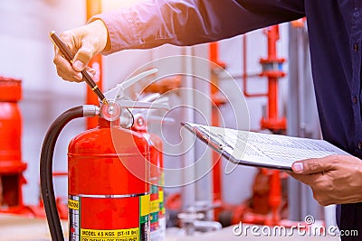 Engineer checking fire extinguisher. Stock Photo