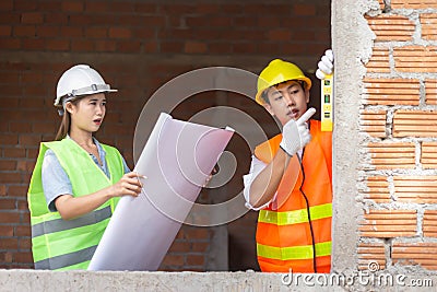 Engineer concept The female constructor holding the building scheme while the constructing guy scaling the surface of the building Stock Photo