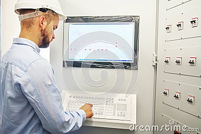 Engineer controls technological equipment from remote control board. Scada system for automation equipment Stock Photo