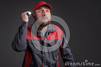 Engineer in a dark basement with a flashlight in his hand looking for a malfunction Stock Photo