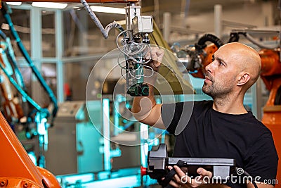 Engineer doing maintenance for automatic robot arms in smart automotive factory, industrial concept Stock Photo