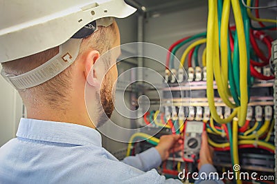 Engineer electric measures multimeter voltage of high-power electrical circuits. Stock Photo