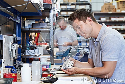 Engineer In Factory Measuring Component At Work Bench Using Micrometer Stock Photo