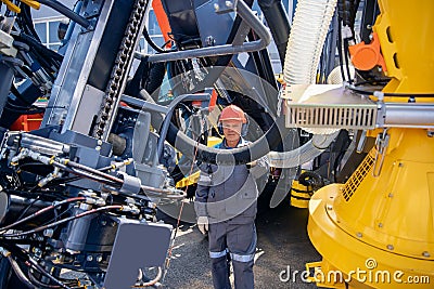 Engineer in hard hat and uniform is servicing hydraulic systems of mining equipment for descending into mine Stock Photo