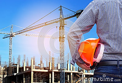 Engineer holding yellow safety helmet in building construction site with crane Stock Photo