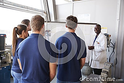 Engineer instructing apprentices at white board, back view Stock Photo