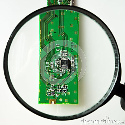 Engineer looking at a circuit board through a magnifying glass Editorial Stock Photo