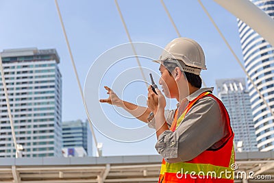 Engineer man in hard hat and safety vest talks on two-way radio at construction site Stock Photo