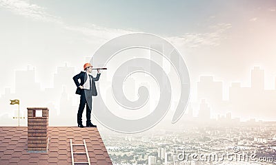 Engineer man standing on roof and looking in spyglass. Mixed med Stock Photo