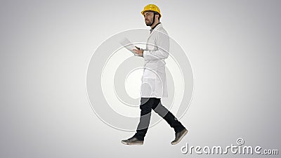 Engineer manager walking with hard hat is holding paper and checking on gradient background. Stock Photo