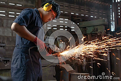 Engineer operating angle grinder hand tools in manufacturing factory - Mechanical engineering student using power tool with hot Stock Photo