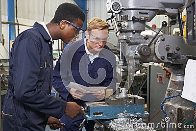 Engineer Showing Apprentice How to Use Drill In Factory Stock Photo