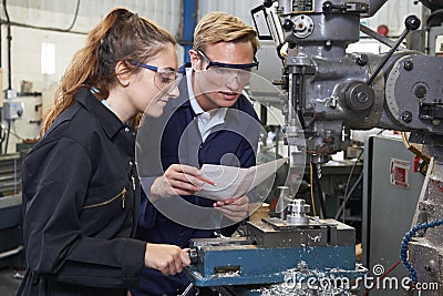 Engineer Showing Apprentice How to Use Drill In Factory Stock Photo