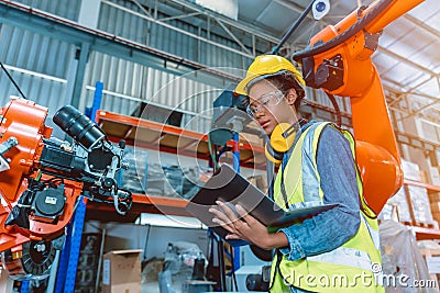 Engineer smart woman worker working programing robotic welding machine. Black teen girl work in advance modern factory Stock Photo
