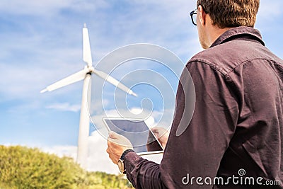 Engineer and tablet in wind power field working for renewable sustainable energy. Technician in industrial electricity generation. Stock Photo