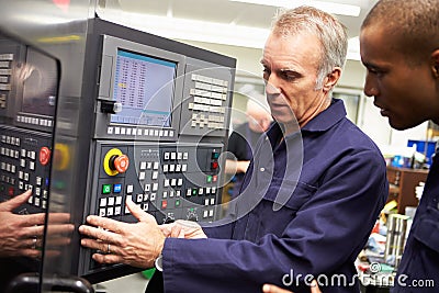 Engineer Teaching Apprentice To Use Computerized Lathe Stock Photo