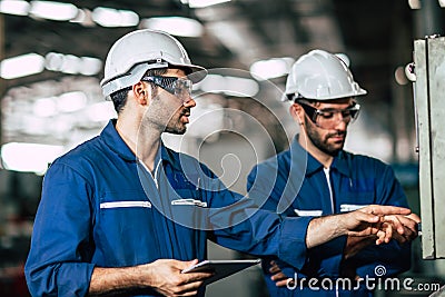 Engineer teamwork checking control panel and teaching new worker to operating control the machine in factory Stock Photo