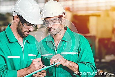 Engineer teamwork cooperate with worker to checking factory machine for safety and talking together.green industry man Stock Photo